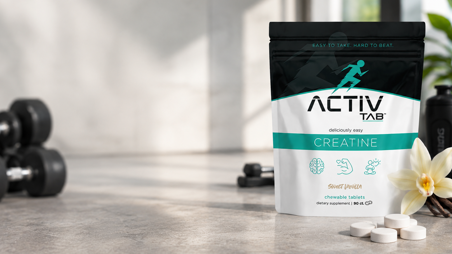 ActivTab Creatine supplement package on a wooden surface with dumbbells and a plant in the background