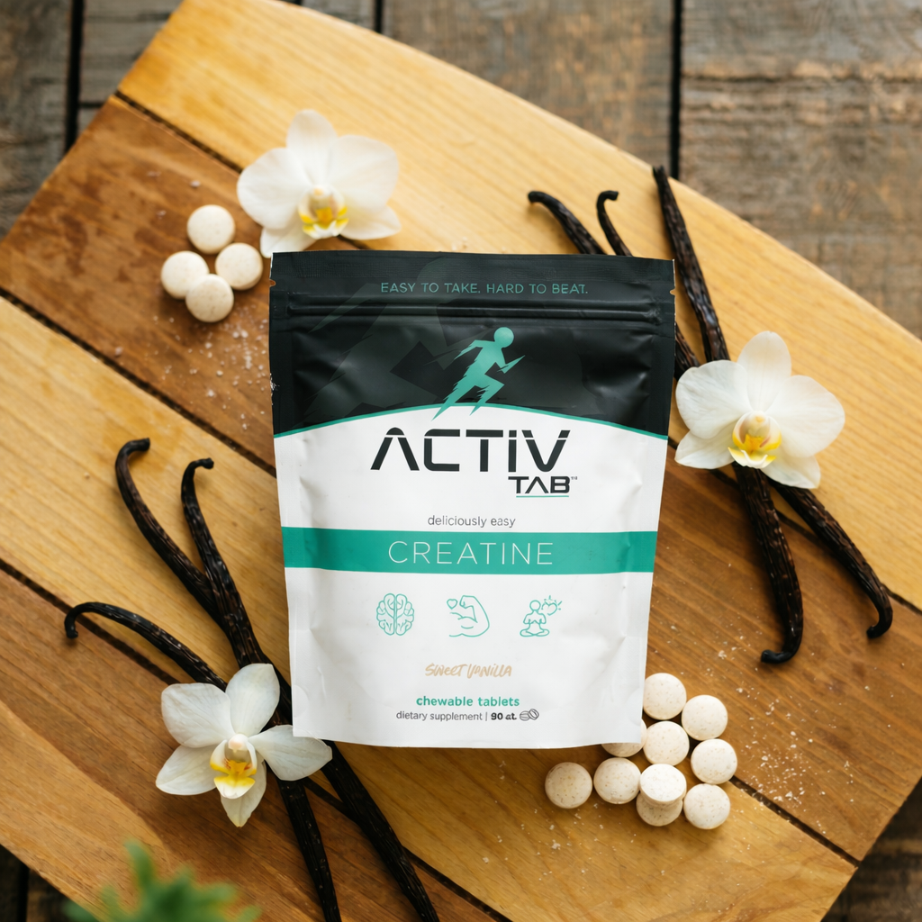 ActivTab creatine supplement package on a wooden surface with vanilla beans and flowers.